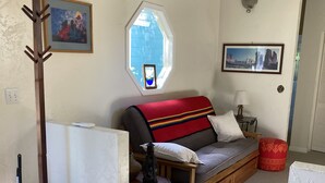 A cozy room with a bed, a window, a lamp, and a coat rack. - Lovely two-bedroom garden suite near Willamette River bike path (Eugene)