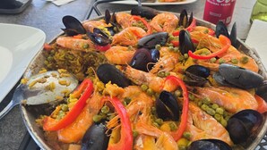 A seafood paella dish on a table with a Coca-Cola can and a green bottle nearby. - NO DISPONIBLE LA CASA. (St. Cloud)