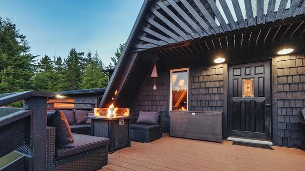 Una terraza exterior con chimenea, zona de estar y puerta con panel de vidrio decorativo.