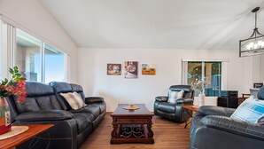 A spacious living room with leather sofas, a wooden coffee table, and artwork on the wall. - Rose Garden Paradise (Peoria)