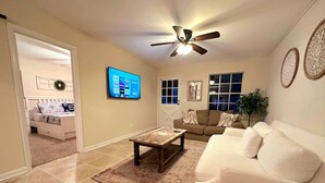 A living room with a white sofa, a wooden coffee table, and a ceiling fan. - Fatima’s Farmhouse: Sleeps8! 4Bd/2Bth/Parking (Jacksonville)