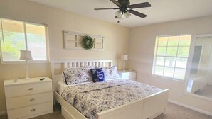 A bedroom with a bed, a nightstand, a dresser, a ceiling fan, and two windows. - Fatima’s Farmhouse: Sleeps8! 4Bd/2Bth/Parking (Jacksonville)