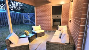 An outdoor patio with wicker furniture and a brick wall. - Fatima’s Farmhouse: Sleeps8! 4Bd/2Bth/Parking (Jacksonville)