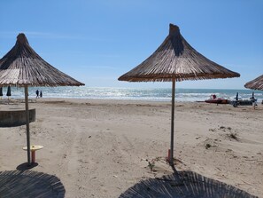 Na praia, areia branca, espreguiçadeiras, guarda-sóis 