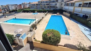 A residential area with two swimming pools, one rectangular and one square, surrounded by buildings. - AGREABLE DEUX PIECES RENOVE DANS UNE RESIDENCE AVEC PISCINE (LE CAP D AGDE)