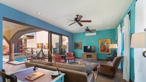 Un vaste espace de vie avec vue sur la piscine, des ventilateurs de plafond et des sièges confortables.