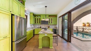 Une cuisine avec des meubles de couleur verte, des appareils électroménagers en acier inoxydable et un îlot central.