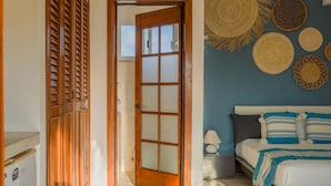 Une chambre à coucher comprenant un lit, une table de chevet et un mur orné d’une décoration murale tissée.