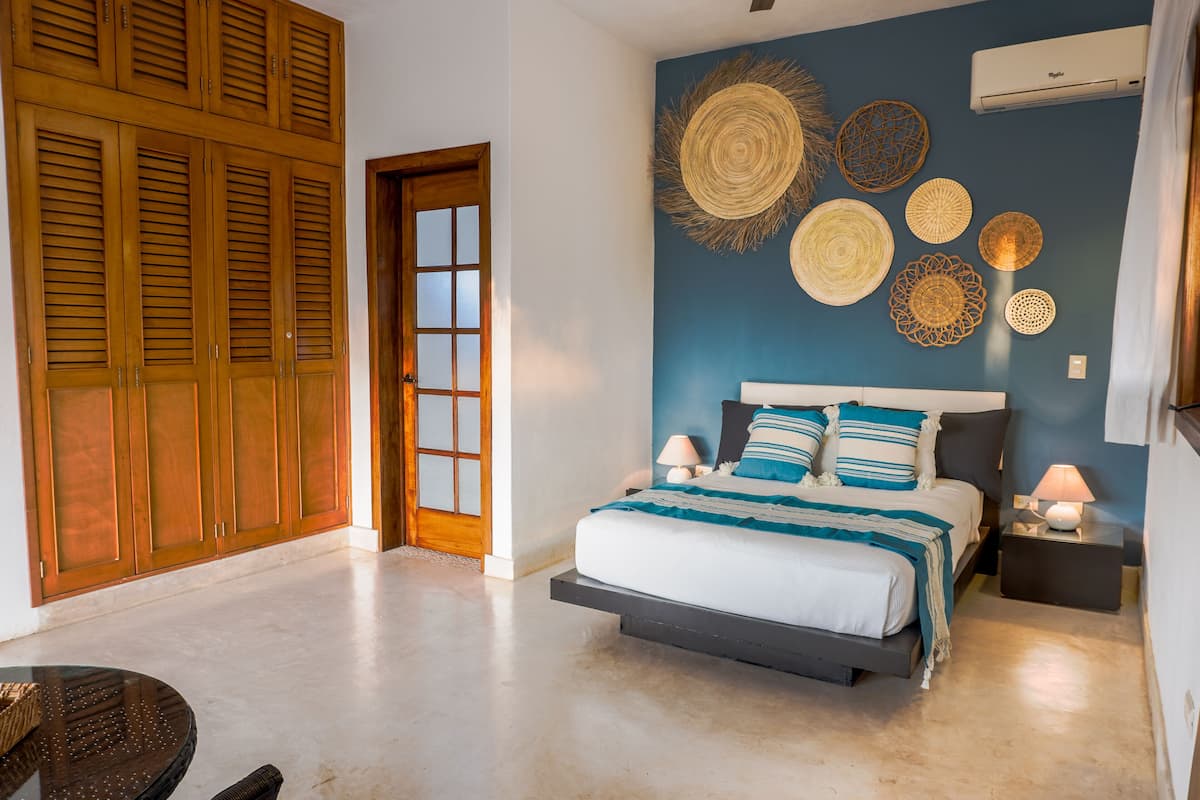 A bedroom with a bed, nightstands, a wooden wardrobe, and decorative wall art.