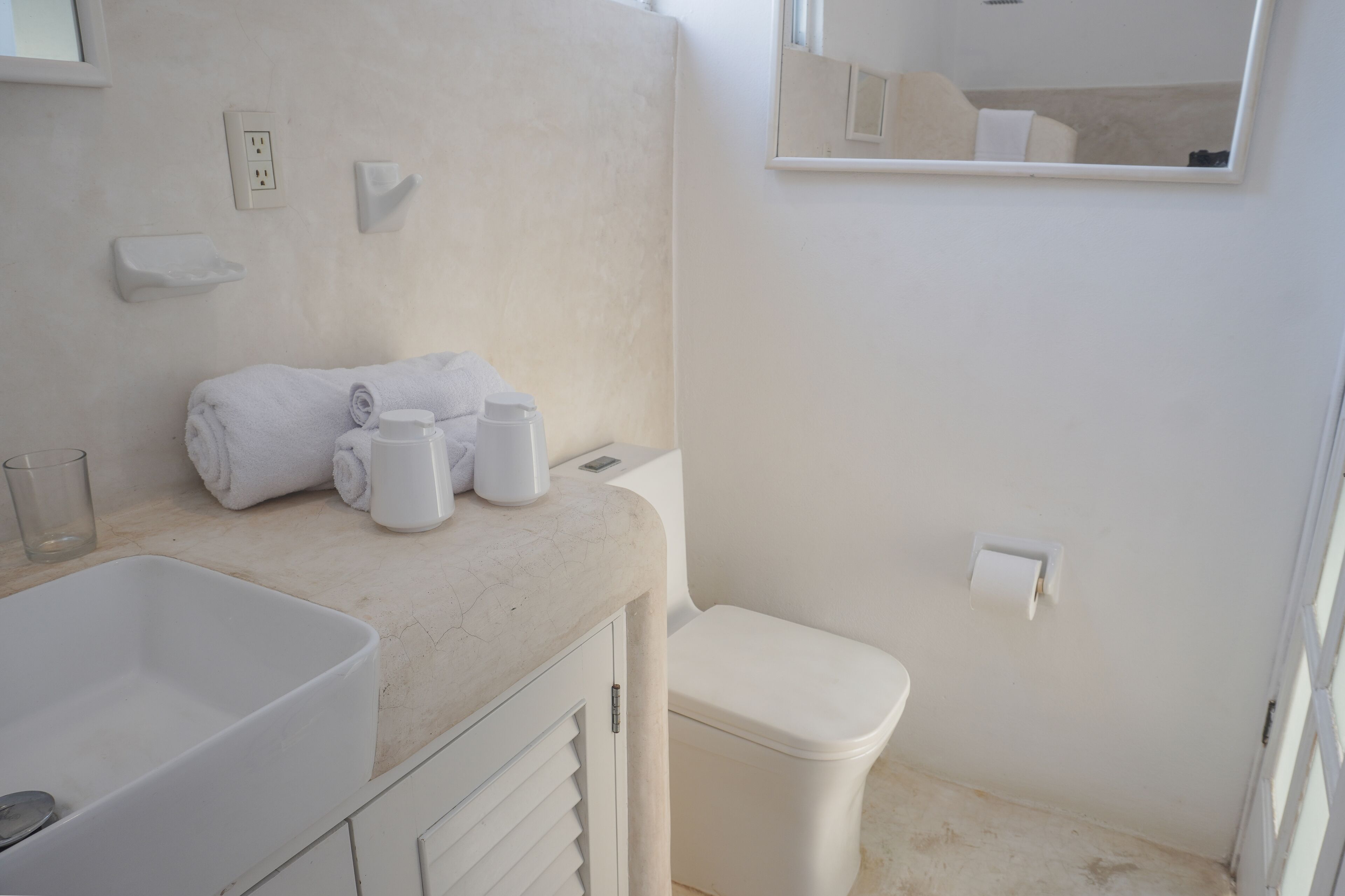 Un baño con lavamanos, inodoro y toallero.
