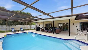 Piscina ao ar livre coberta com espreguiçadeiras e área de churrasco.