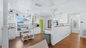 A modern kitchen with white cabinetry, a wooden countertop, and a stainless steel refrigerator.