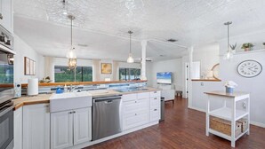 A modern kitchen with white cabinetry, a central island, and pendant lighting.