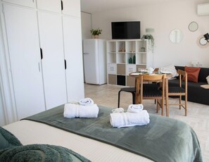 A hotel room with a bed, a desk with a chair, a sofa, a TV, and a wardrobe. - Elegant Studio With Marina Sea And Esterel View (Mandelieu-la-Napoule)