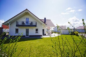 A two-story house with a balcony, a covered patio, and a well-maintained lawn.