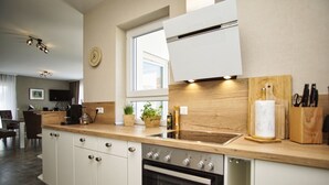 A modern kitchen with white cabinetry, a built-in oven, a sink, and a wooden countertop.