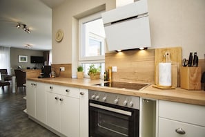 Eine moderne Küche mit weißen Schränken, einem Einbauofen, einer Spüle und einer Holz Arbeitsplatte.
