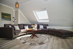 Ein modernes Wohnzimmer mit einer Eckcouch, einem runden Couchtisch und einem Dachfenster.