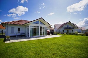 A residential area with two houses, one with a glass extension, and a well-maintained lawn.