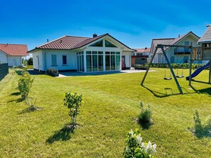 A residential area with houses, a grassy yard, and a swing set. - Ferienhaus Windrose - Modernes Haus mit Kamin und Eigener Sauna Sowie Garten - Ferienhaus Windrose (Trent)