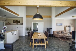 Een ruime woonkamer met een houten eettafel, leren banken en een moderne hanglamp.