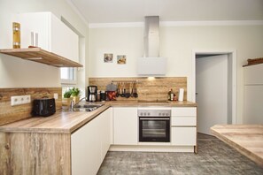Una cocina moderna con encimeras de madera, horno empotrado y cafetera.