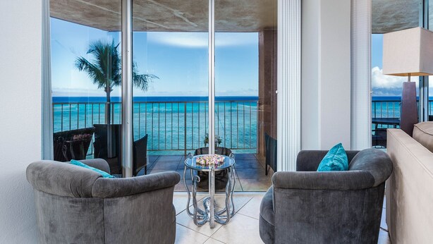 Een balkon met uitzicht op de oceaan, ingericht met twee fauteuils en een klein tafeltje.