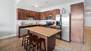 Une cuisine moderne avec des meubles en bois, des appareils en acier inoxydable et un îlot central doté de tabourets.