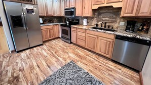Una cocina con armarios de madera, electrodomésticos de acero inoxidable y una alfombra estampada.