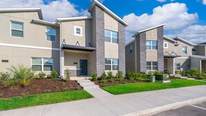 A modern multi-story residential building with a flat roof, large windows, and a well-maintained lawn. - RH4415 Townhouse 5/4 Private Pool & Free Waterpark (Kissimmee)