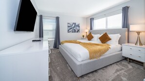A modern bedroom with a bed, bedside tables, a TV, and artwork on the wall. - RH4415 Townhouse 5/4 Private Pool & Free Waterpark (Kissimmee)