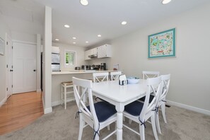 Una cocina moderna con armarios blancos, una mesa de comedor con cuatro sillas y un mapa en la pared.