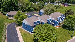 Una zona residencial con varias casas azules, un camino pavimentado y un árbol grande.