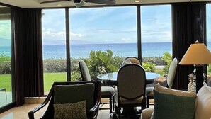 Un salon moderne avec une grande table en verre, des sièges confortables et une vue sur l’océan.