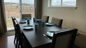 A dining table set with plates, cups, and cutlery, with chairs around it.