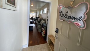 A hallway leading to a living area with a 'Welcome' sign, a dining area, and a kitchen.