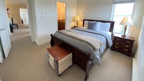 A bedroom with a bed, bedside tables, a nightstand, a lamp, and a window.
