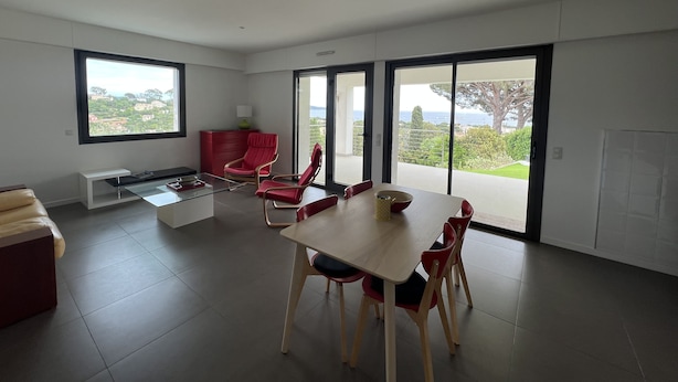 A modern living room with a dining area, large windows, and a view of the outdoors. - Ground floor villa with private pool (Cavalaire-sur-Mer)