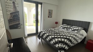 A bedroom with a bed, a desk, a door leading to a balcony, and a poster on the wall. - Ground floor villa with private pool (Cavalaire-sur-Mer)