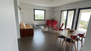 A modern living room with a dining area, large windows, and a view of greenery. - Ground floor villa with private pool (Cavalaire-sur-Mer)