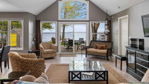 A spacious living room with a large glass coffee table, comfortable seating, and a view of the outdoors. - Northern Tranquility on Black Lake
Available the weeks of July 11 and July 18!!! (Cheboygan)