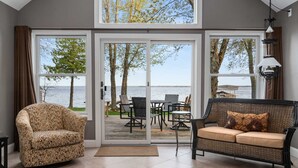 A room with a large sliding glass door leading to an outdoor deck with a view of the water. There are two sofas and a chair inside the room. - Northern Tranquility on Black Lake
Available the weeks of July 11 and July 18!!! (Cheboygan)