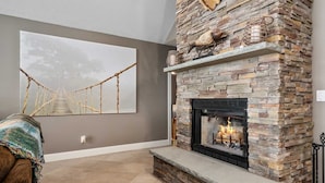 A living room with a stone fireplace, a large abstract painting, and a cozy seating area. - Northern Tranquility on Black Lake
Available the weeks of July 11 and July 18!!! (Cheboygan)
