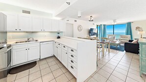 A modern kitchen with white cabinets, a central island, and a dining area with a view.