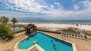 A swimming pool with lounge chairs and a beach view.