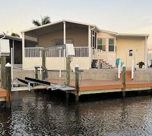 A waterfront house with a dock, a covered porch, and a staircase leading to the entrance.