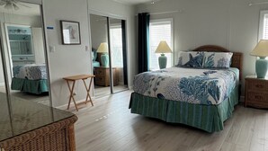A bedroom with a bed, bedside tables, a mirror, and a dresser.