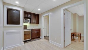 A kitchen with wooden cabinets, a microwave, and a small table. - Ski in/out Disciples Boyne Moun. All Seasons Suite (Boyne Falls)