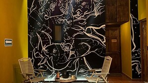 A room with a black wall featuring a white line drawing of a tree and a chair on each side. There are three pendant lights hanging from the ceiling. - Ideal Family Loft, Comfortable in the Heart of Val'quirico (Domingo Arenas)