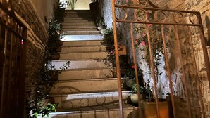 A stone staircase with metal railings, potted plants, and a view of a building at the top. - Ideal Family Loft, Comfortable in the Heart of Val'quirico (Domingo Arenas)